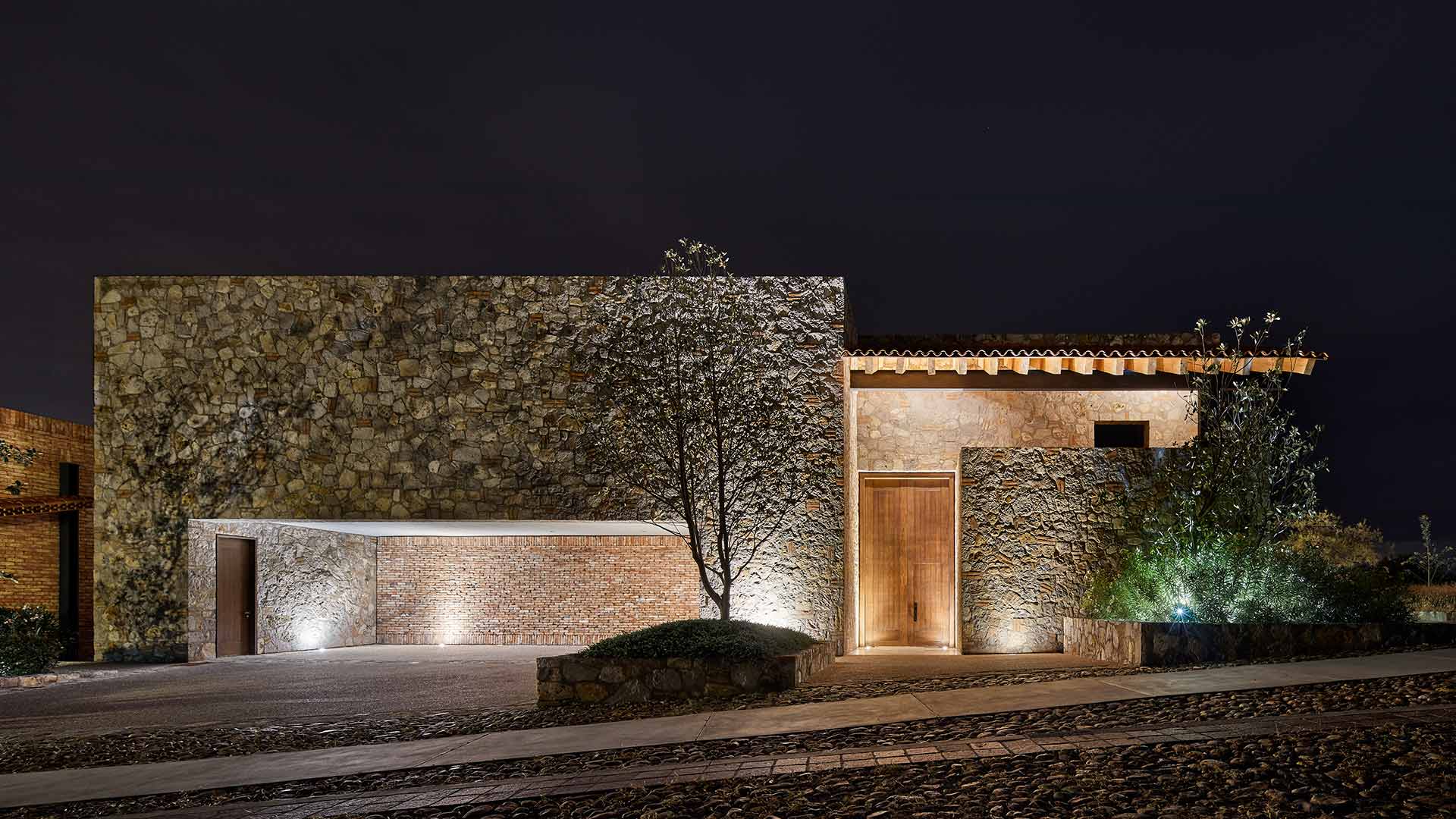 Fachada de piedra de una residencia Farré iluminada de noche